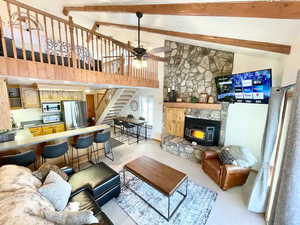 Living area with stairway, high vaulted ceiling, ceiling fan, beamed ceiling, and a wood stove