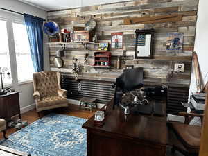 Office with bar, wood walls, baseboards, and wood finished floors