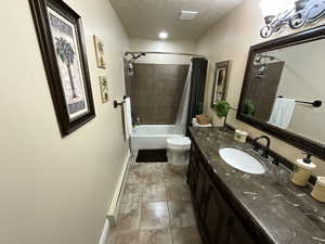 Bathroom featuring toilet, vanity, shower / bath combo, baseboards, and a baseboard heating unit