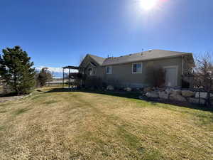 Rear view of property featuring roof with shingles, stucco siding, and a yard