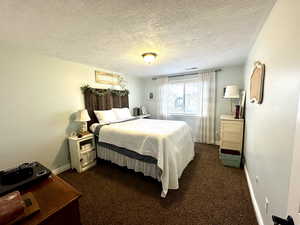 Bedroom featuring visible vents, baseboards, dark carpet, and a textured ceiling