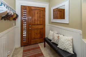 Foyer entrance featuring a wainscoted wall, tile patterned floors, and a wealth of natural light