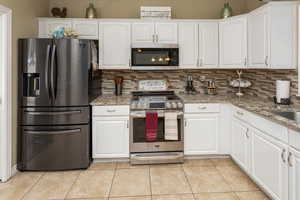 Kitchen with white cabinetry, tasteful backsplash, appliances with stainless steel finishes, and light tile patterned floors