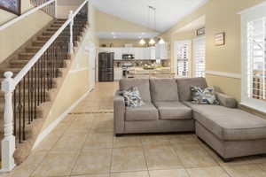 Living room featuring light tile patterned floors, a chandelier, and stairs