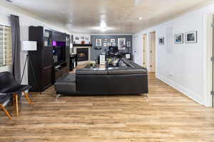 Living area featuring light wood finished floors, baseboards, a tile fireplace, and ornamental molding