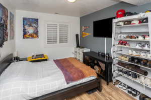 Bedroom featuring a textured ceiling, visible vents, and light wood-type flooring