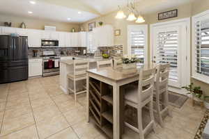 Kitchen with white cabinetry, tasteful backsplash, light tile patterned flooring, light stone counters, and appliances with stainless steel finishes