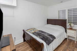 Bedroom with baseboards, visible vents, and wood finished floors
