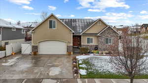 View of front of house with stucco siding, a gate, stone siding, and a garage