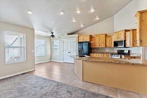 Kitchen with ceiling fan, light tile patterned floors, appliances with stainless steel finishes, light stone counters, and a sink