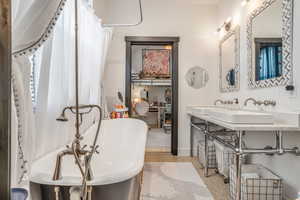 Bathroom featuring speckled floor, baseboards, a sink, and a soaking tub