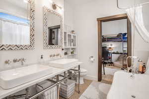 Bathroom featuring baseboards, a sink, toilet, and a soaking tub