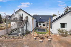 Rear view of property featuring stucco siding, stairs, a fire pit, solar panels, and a patio area