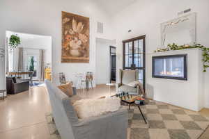 Living area featuring a towering ceiling, visible vents, and a glass covered fireplace