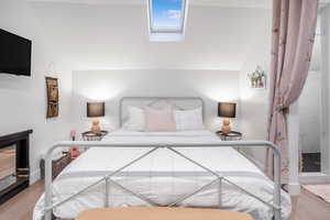 Bedroom with lofted ceiling with skylight and wood finished floors