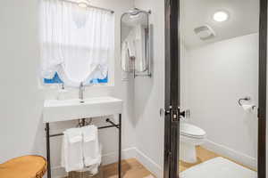 Bathroom with baseboards, wood finished floors, toilet, and a sink