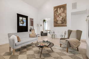 Living area with high vaulted ceiling, baseboards, and visible vents