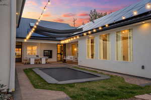 Rear view of property with outdoor dry bar, a standing seam roof, stucco siding, metal roof, and a patio area