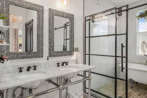 Bathroom featuring a sink, a chandelier, a shower stall, and a freestanding bath