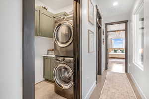 Laundry area with visible vents, cabinet space, baseboards, and stacked washer / drying machine