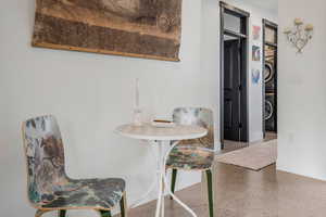Dining room featuring baseboards, speckled floor, and stacked washing maching and dryer