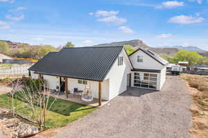 Rear view of house with stucco siding, a patio, metal roof, driveway, and a mountain view