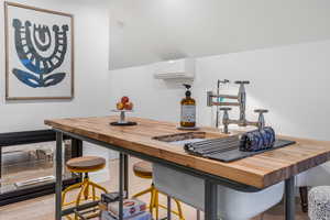 Kitchen with butcher block countertops, a wall mounted AC, a sink, and wood finished floors