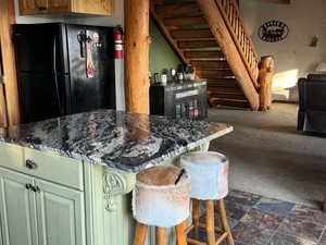Kitchen featuring carpet floors, green cabinetry, and freestanding refrigerator