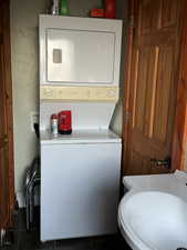 Clothes washing area featuring a sink, stacked washing maching and dryer, and laundry area