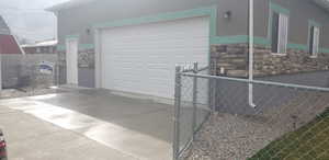 Garage with concrete driveway, fence, and a gate
