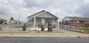 View of front facade with stone siding, a gate, a porch, and a fenced front yard
