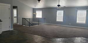 Carpeted empty room featuring healthy amount of natural light, baseboards, ceiling fan, and vaulted ceiling