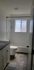 Bathroom with toilet, vanity, and  shower combination