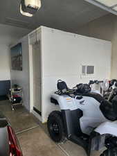 Garage featuring a garage door opener and a wall unit AC