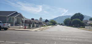 View of asphalt road with sidewalks, a residential view, a mountain view, and curbs