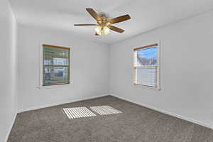 Unfurnished room featuring carpet floors, baseboards, and ceiling fan