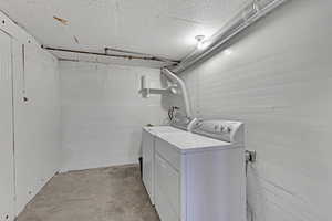 Laundry area with independent washer and dryer, concrete block wall, and laundry area