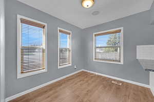 Empty room with light wood-style floors, baseboards, and visible vents