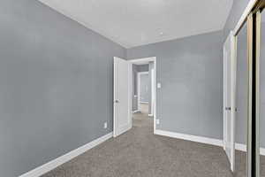 Unfurnished bedroom featuring a closet, baseboards, carpet flooring, and a textured ceiling