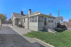 Back of property with a chimney, central AC unit, entry steps, fence, and a lawn