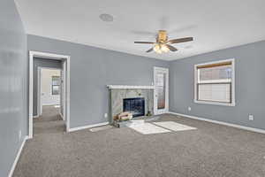 Unfurnished living room with a healthy amount of sunlight, a high end fireplace, baseboards, and carpet