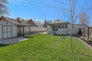 View of yard featuring a sunroom, a fenced backyard, an outdoor structure, an outdoor fire pit, and a storage unit