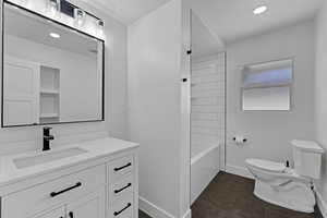 Full bathroom with toilet, vanity, baseboards, and tile patterned flooring