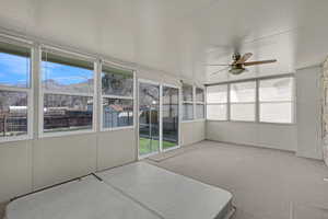 Unfurnished sunroom featuring a healthy amount of sunlight and a ceiling fan