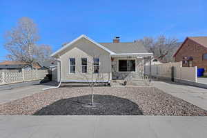 Bungalow with fence, stone siding, stucco siding, and a chimney