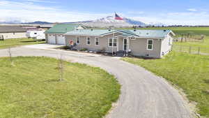View of front facade with fence, dirt driveway, a mountain view, and metal roof
