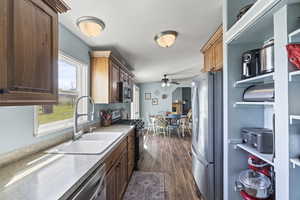 Kitchen with dark wood finished floors, light countertops, a sink, appliances with stainless steel finishes, and ceiling fan