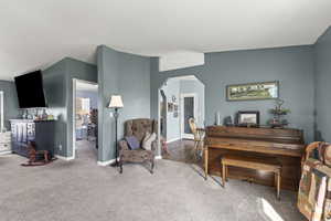 Living area with arched walkways, carpet flooring, and baseboards