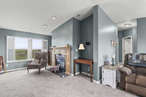 Carpeted living room featuring a fireplace with flush hearth and baseboards