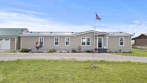 View of front of property featuring fence, crawl space, a front yard, and metal roof